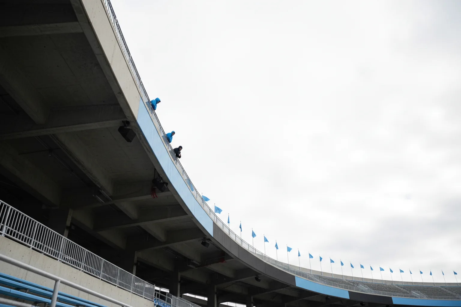 Low angle looking up at a stadium's upper tier and pennants against a bright overcast sky
