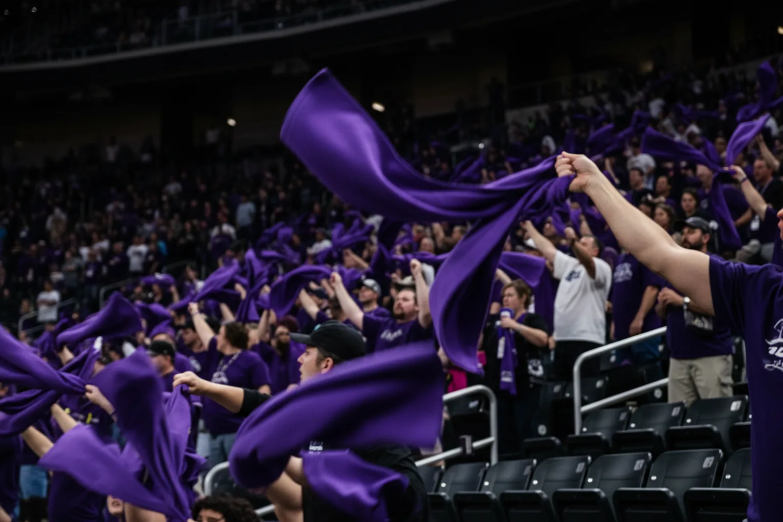 Purple rally towels swung overhead, blurred into overlapping arcs in a dark arena